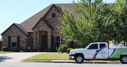 Weed Control NWA service truck parked outside a brick home with treated lawn
